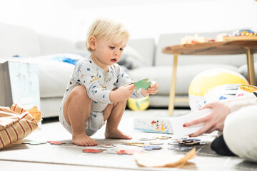 Parents playing games with child. Little toddler doing puzzle. Infant baby boy learns to solve problems and develops cognitive skills. Child development concept. - 748774181