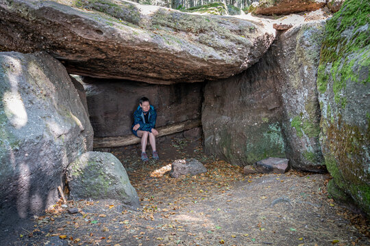 Mont Sainte Odile, France - 09 11 2020: Path of the Gauls. View of a hiker woman sitting in the druids' cave .
