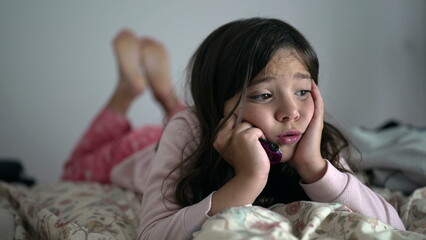 One bored little girl feeling extreme boredom with nothing to do laid in bed with hands in chin....