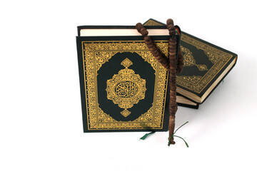 The Holy Quran with Arabic calligraphy, meaning The Noble Quran, and a tasbih, isolated on a white background