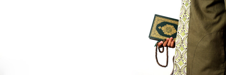An Indonesian Muslim man holding the Holy Quran and tasbih on a white background prepares to perform Itikaf at a mosque during the last ten days of Ramadan, seeking spiritual reflection and renewal