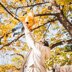 More, more,... dad, that's fun. Happy young father throws his cute little happy baby boy up in the air. Father's Day, Father and his son baby boy playing and hugging outdoors in nature in fall - 748783704