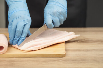 Fat is cut into small pieces. Hands of a cook cutting lard with a knife into small pieces to...