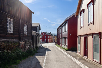 A sunlit street in Roros offers a glimpse into Norwegian history with its colorful wooden facades and peaceful urban scenery, typical of a tranquil Nordic village - obrazy, fototapety, plakaty