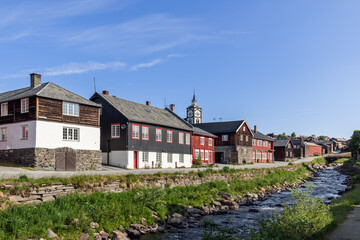 Fototapeta na wymiar Roros presents a harmonious riverside setting where historic wooden architecture and the prominent church clock tower capture the essence of this Norwegian heritage town