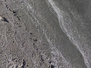The texture of fine gray sea sand with small stones