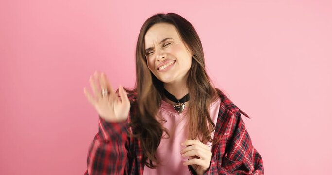 Brunette woman listen someone, wave her hand with sign no matter, don't think about it, all right. I needn't your help, i'll be fine standing isolated on pink background.