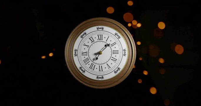 Animation of retro clock ticking showing midnight with spots of light on black background