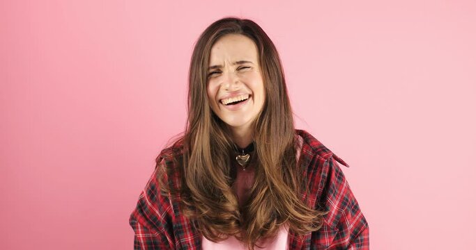 Happy joyful young woman wear pink sweater laughing out loud after hearing ridiculous anecdote, funny joke, feeling carefree amused, positive lifestyle isolated on pink background