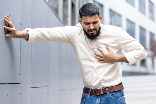 Man in pain clutching chest experiencing sudden heart attack outdoors