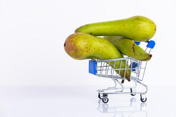 Green conference pears in a shopping cart, on a white background. Copy space.