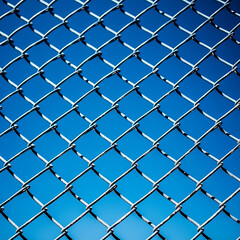 Fototapeta premium A chain link fence on a blue background, 1:1.