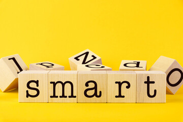 The word, SMART. Wooden cubes with letters on a yellow background. Conceptual image.