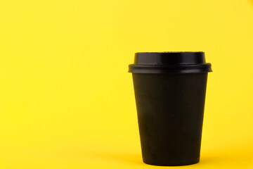 Black paper eco cup, coffee paper cup on yellow background. Mockup for your advertisement
