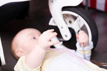 Boy mechanic repairs the suspension of a baby carriage. We repair everything that travels. Humor,...