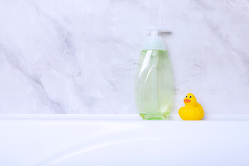 Children's hygiene products concept. Yellow duckling in the bathroom on a background of gray tiles. Copy space