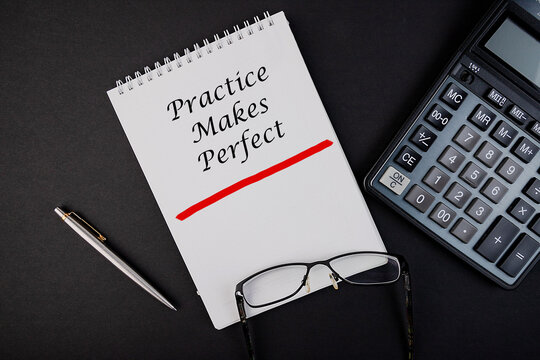 Practice makes perfect notepad writing concept on dark background with pen and calculator.