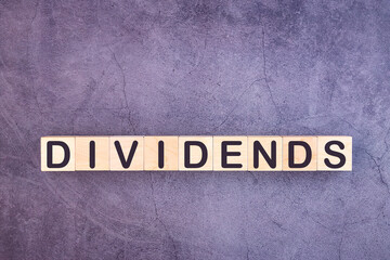 DIVIDENDS word made with building blocks on a grey background