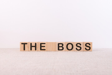 THE BOSS word concept written on wooden cubes lying on a light table and light background.