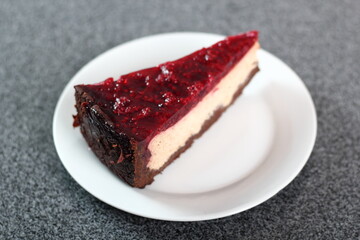 Cheesecake with chocolate crumb base topped with raspberry jelly