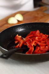 Sliced raw red bell pepper in frying pan. Making Chicken and Egg Galette Series.
