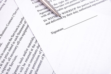 Obraz premium Pen resting above signature line of document. Focus on tip of pen nib.