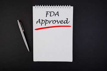 FDA Approved text, inscription, phrase is written in a notebook that lies on a dark table and a pen. Business concept.