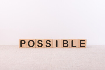 POSSIBLE word concept written on wooden cubes lying on a light table and light background.