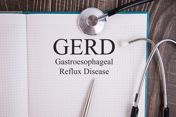 Notebook page with GERD Gastroesophagea l Reflux Disease text, on a table with a stethoscope and pen, medical concept. - obrazy, fototapety, plakaty