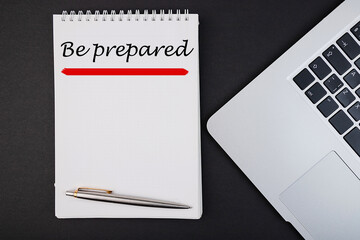 Be prepared text, inscription, phrase written in a notebook that lies on a dark table with a laptop...