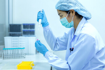 Women scientists are using aqueous release micro-pipette into the test tube. The process of...