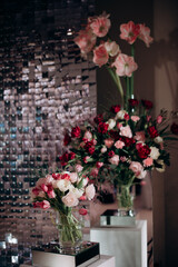 The wedding reception is decorated with glass vases, filled with white and pink tulips, surrounded...