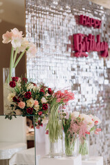 The wedding reception is decorated with glass vases, filled with white and pink tulips, surrounded by burning candles, which creates an intimate romantic atmosphere, close-up. Photo zone for a couple 