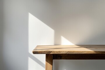 Minimalist wooden table against a white wall with sunlight casting a shadow