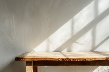 Minimalist wooden table against a white wall with sunlight casting a shadow