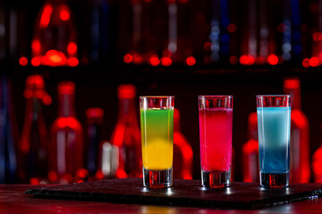 Cocktails Party Shots and Shooters on bar counter in a restaurant, pub. Miniature mixed drinks. Alcoholic cooler beverage at nightclub on dark background