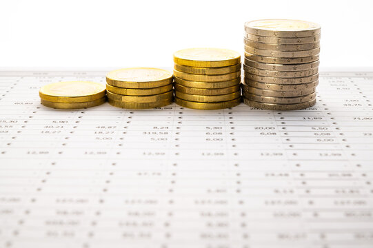 Table with calculations, budget, and stacks of coins; increase or decrease in money or budget.
