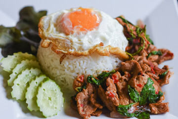 Pork with basil and fried egg on rice is ready to eat on the table.