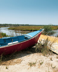 Peaceful landscape with a boat next to a wooden pier. Rice fields in the distance. Comporta, Portugal, Europe.
