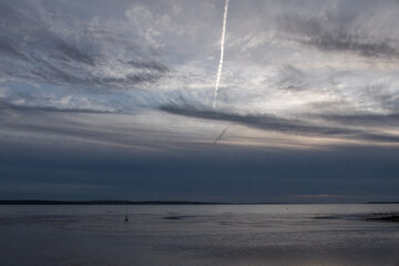 vapour trail and stormy sky at sunset over the sea