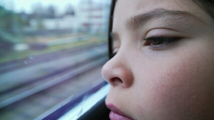 One little girl opening eyes leaning on train window, close-up pensive female 8 year old child gazing at landscape pass by inside high-speed transportation