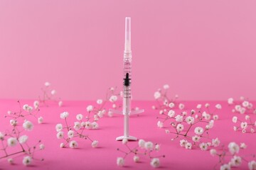 Cosmetology. Medical syringe and gypsophila flowers on pink background