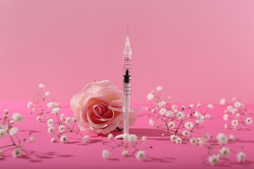 Cosmetology. Medical syringe, rose and gypsophila flowers on pink background
