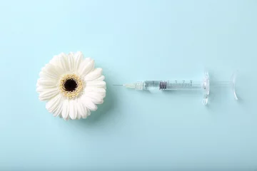 Fotobehang Cosmetology. Medical syringe and gerbera flower on light blue background, flat lay © New Africa