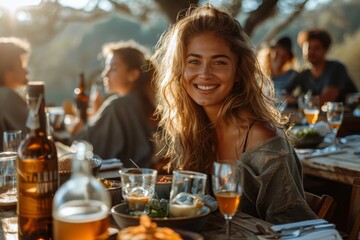 Cheerful woman enjoying a sunset dinner surrounded by friends at an outdoor table - obrazy, fototapety, plakaty