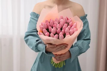 Fotobehang Woman holding bouquet of pink tulips indoors, closeup © New Africa