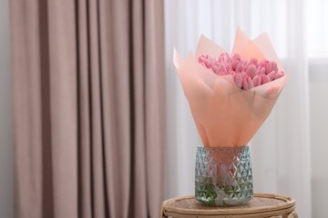 Bouquet of beautiful pink tulips in vase on table indoors, space for text