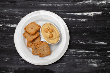 a bowl of hummus dip with mini toasts