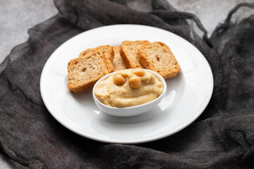 a bowl of hummus dip with mini toasts