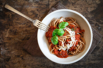 Bowl with spelt whole grain spaghetti, tomato sauce, parmesan and basil